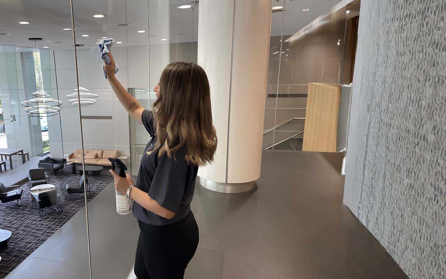 Hotel cleaning staff wiping and disinfecting surfaces in a common area to maintain cleanliness and hygiene.